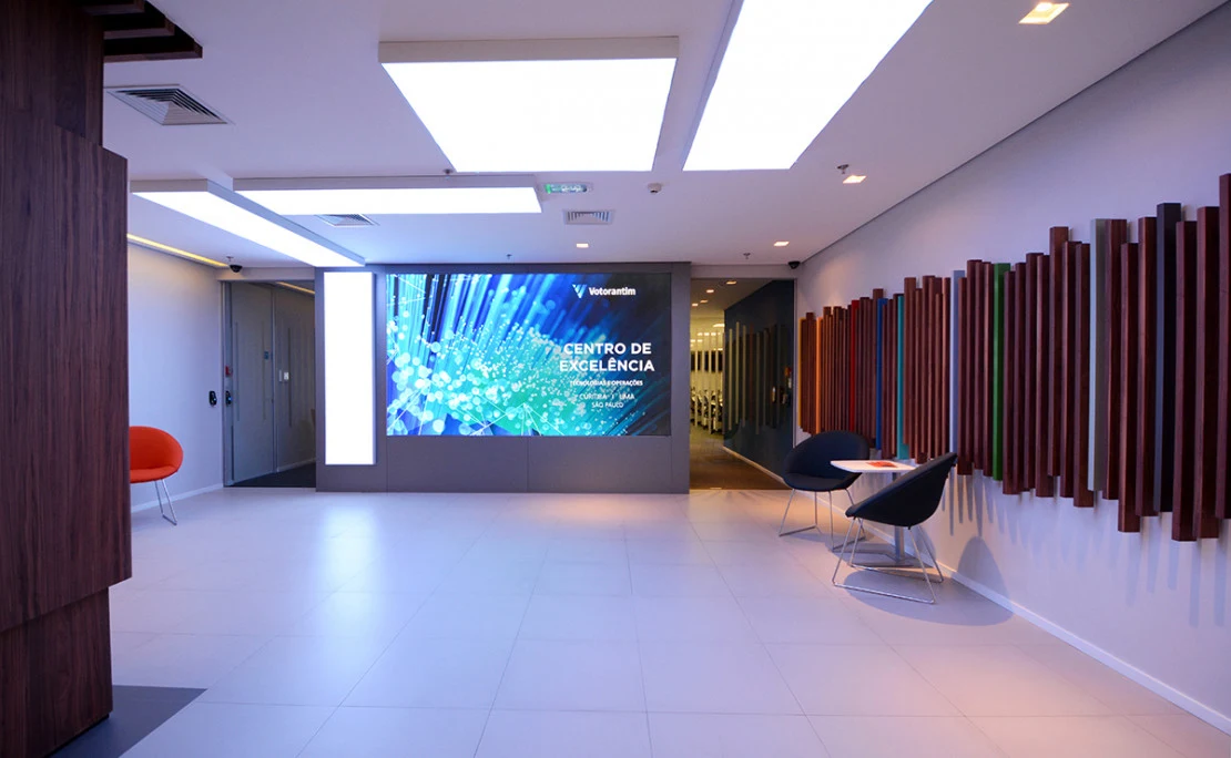 Recepção do Centro de Excelência Votorantim, com painel da marca e área de convivência
